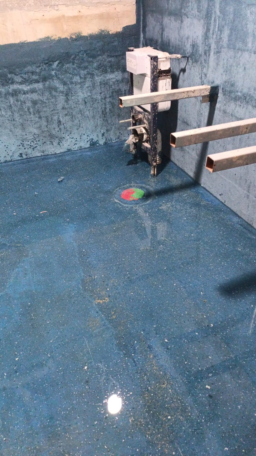 Blue waterproofing membrane around wall-hung cistern and floor trap
