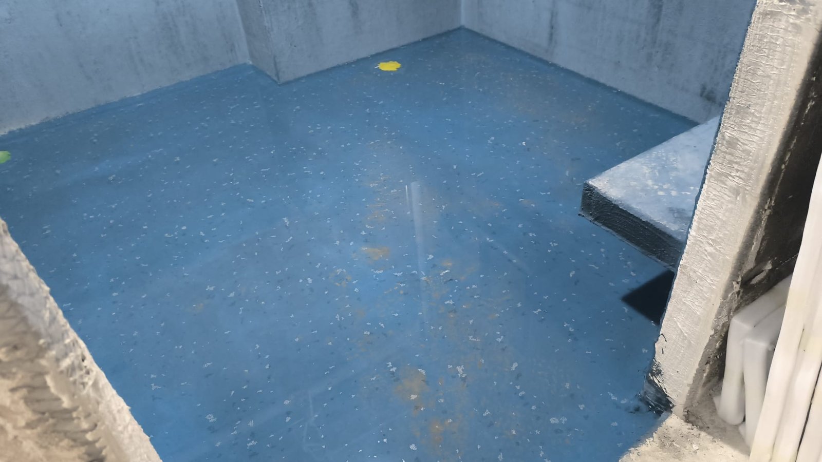 Wet-area floor and wall upturns coated with blue waterproofing membrane
