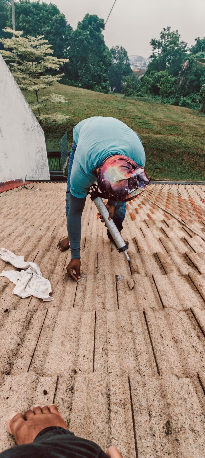 Worker sealing roof tiles with a caulking gun